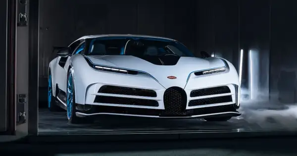 Biały Bugatti Centodieci z niebieskimi akcentami i felgami, otoczony mgłą i pionowymi światłami.