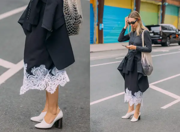 Elegancka koronkowa spódnica stylizacje z czarną marynarką i siatkową torbą. Kobieta w okularach przeciwsłonecznych i szarej bluzce z długim rękawem.