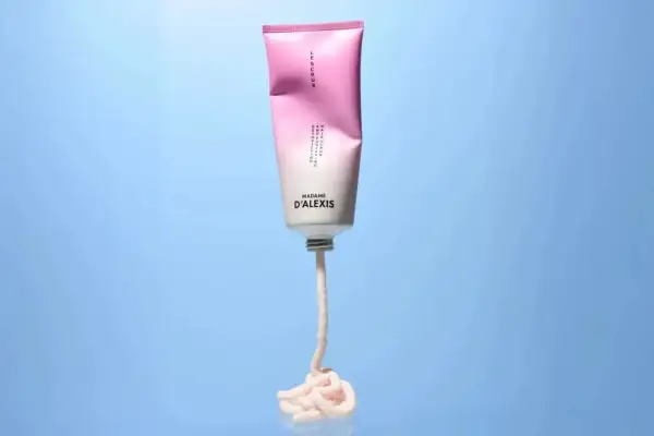 Tube de scrub rose et blanc Madame D'Alexis, produit pour un detox cuir chevelu, avec une texture crémeuse qui s'écoule.