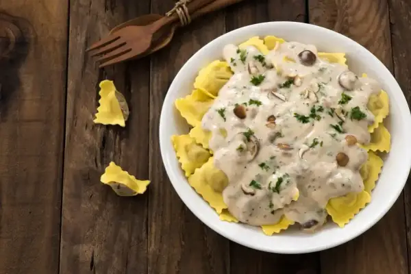 Pyszne ravioli w kremowym sosie śmietanowym z grzybami i natką pietruszki. Idealny sos śmietanowy do makaronu.
