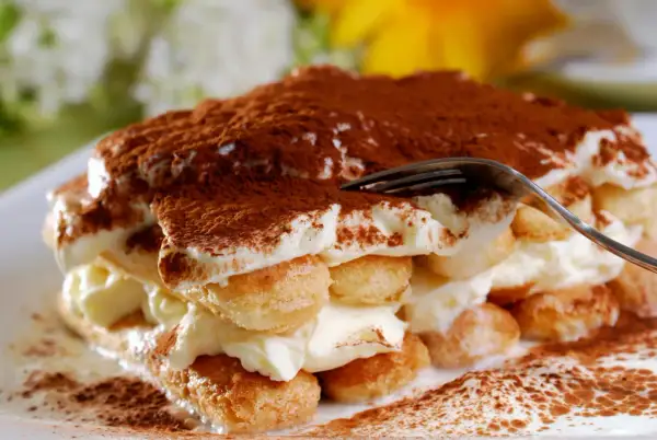 Un tiramisu crémeux, saupoudré de cacao. Pour un goût optimal, demandez-vous combien de temps laisser reposer un tiramisu au frigo.