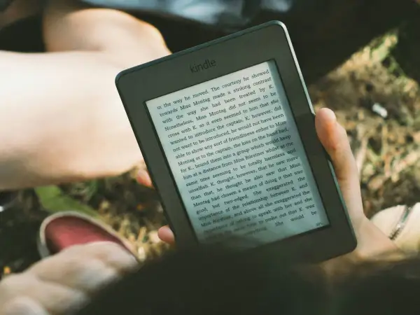 Osoba czyta książkę na czytniku Kindle, korzystając z Legimi.