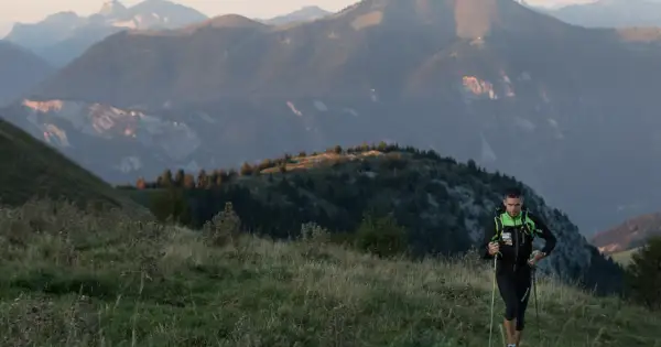 Un coureur en plein effort, bâtons en main, sur un sentier de montagne. Un aperçu de son plan d'entraînement UTMB.