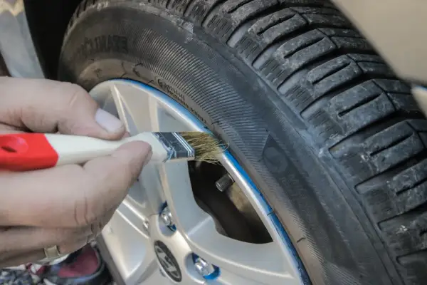 Ręczne malowanie felgi pędzlem, pokazujące zastosowanie gumy w sprayu do tuningu wizualnego opon.