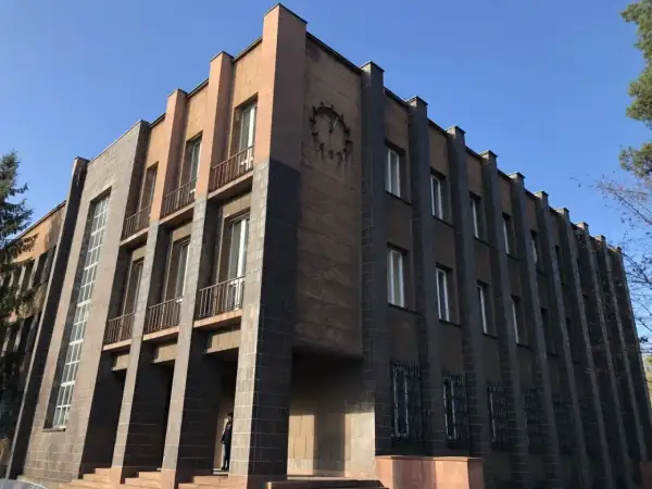 Monumentalny budynek z zegarem, przykład art deco w Polsce. Geometryczne formy, ciemna i jasna elewacja, wąskie okna.