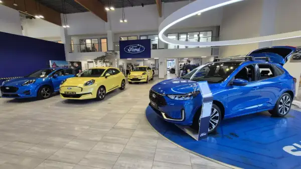 Salon Forda z kilkoma nowymi autami, w tym niebieskim SUV-em. Zastanawiasz się, auto w leasingu co to znaczy? To opcja dla Ciebie!