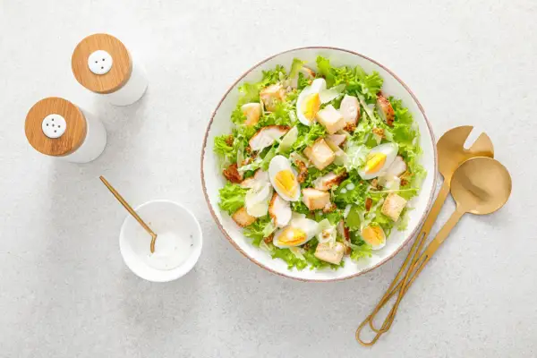 Insalata di pollo sfiziosa con uova sode, crostini e scaglie di parmigiano. Perfetta per un pranzo leggero e gustoso.