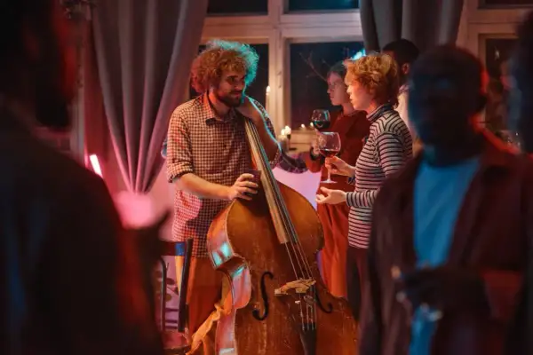 Muzyk z kontrabasem i goście z winem. Idealny strój na koncert jazzowy to swobodna elegancja.