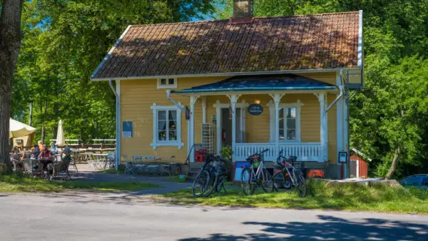 Gult hus med café & vandrarhem. Cyklar står parkerade framför. Folk sitter vid bord utomhus.