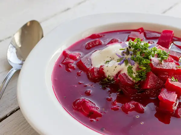 Herzhafte Rote-Bete-Suppe mit einem Klecks Sauerrahm und frischer Petersilie. Ein köstliches Gericht, das an Borretsch Rezepte erinnert.
