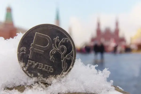 Moneta z symbolem rubla, wskazująca, jaka waluta obowiązuje w Rosji, na tle ośnieżonego placu Czerwonego.