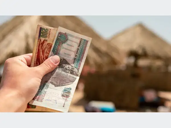 Ręka trzyma banknoty 100 i 200 funtów egipskich. Planujesz podróż do Egiptu i zastanawiasz się, jakie dolary zabrać?