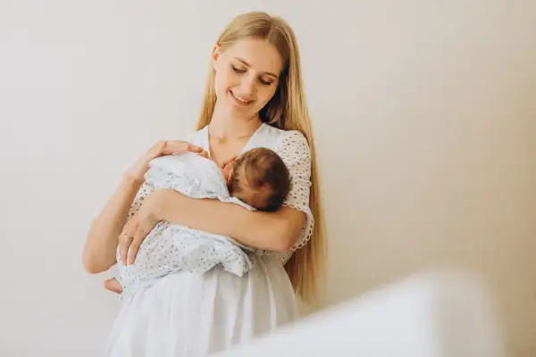 Szczęśliwa mama z niemowlęciem na rękach. To piękny okres karmienia piersią, pełen bliskości i miłości.