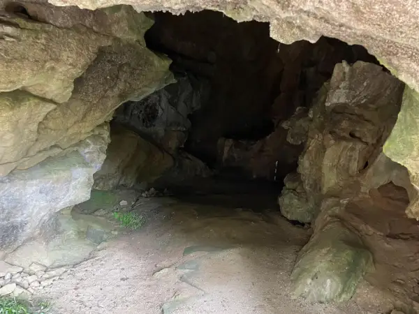 Entrada a la cueva de la Loja, con rocas irregulares y un camino de tierra que se adentra en la oscuridad.