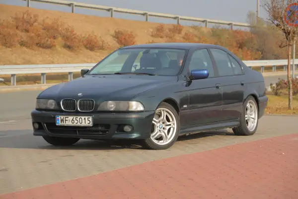 Ciemnozielone BMW E39 z polskimi tablicami WF 65015 stoi na parkingu.