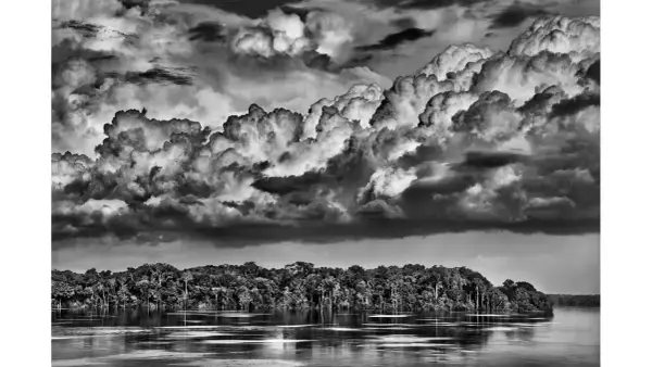 Dramatyczne chmury nad Amazonką, uchwycone przez Sebastiao Salgado. Potężna rzeka i bujna dżungla.