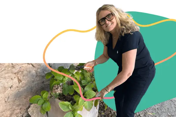 Une femme souriante jardine, un exemple de loisirs pour jeunes retraités actifs et épanouis.