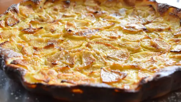 Une flognarde aux pommes dorée et appétissante, saupoudrée de sucre glace. Un délice fait maison.