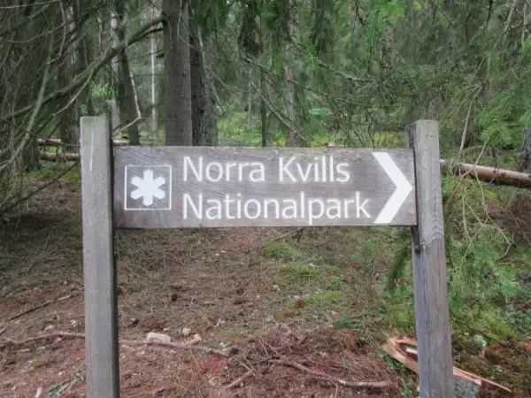 Skylt visar vägen till Norra Kvills Nationalpark genom en tät skog.