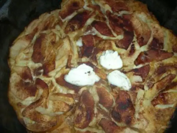 Ein frisch gebackener Apfel-Scheiterhaufen mit Zimt und drei Klecksen Sahne. Ein köstliches Rezept für gemütliche Stunden.