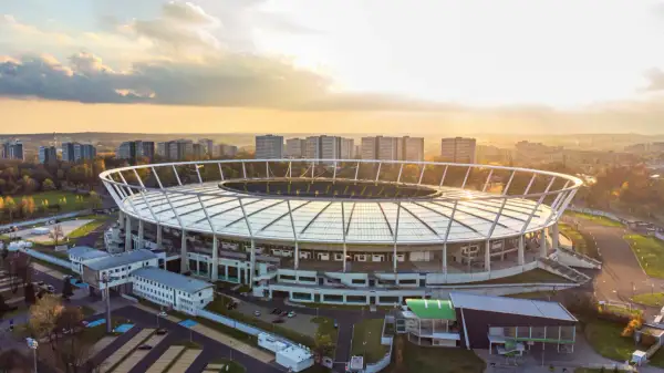 Stadion Śląski w Chorzowie o zachodzie słońca. Obiekt, który gościł niezliczone koncerty, otoczony jest zabudową miejską i zielenią.