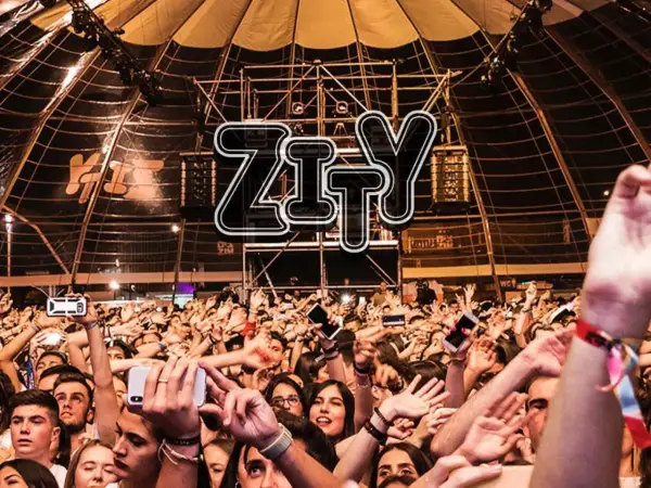 Multitud animada en la entrada del espacio Zity, con brazos en alto y móviles grabando el evento.