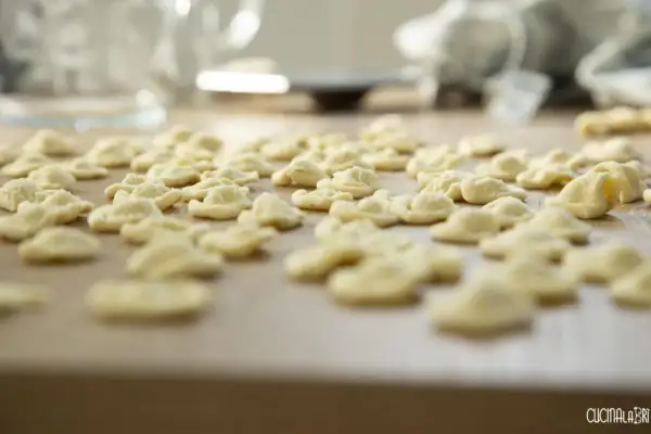 Orecchiette fatte in casa, pronte per essere cucinate. Un mare di pasta fresca su un tagliere di legno.