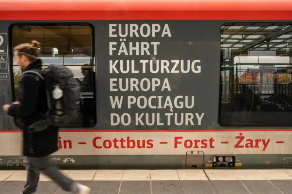 Ein Mann mit Rucksack steigt in einen Zug, der von Berlin nach Breslau fährt. Der Schriftzug "Europa fährt Kulturzug" ziert die Seite.