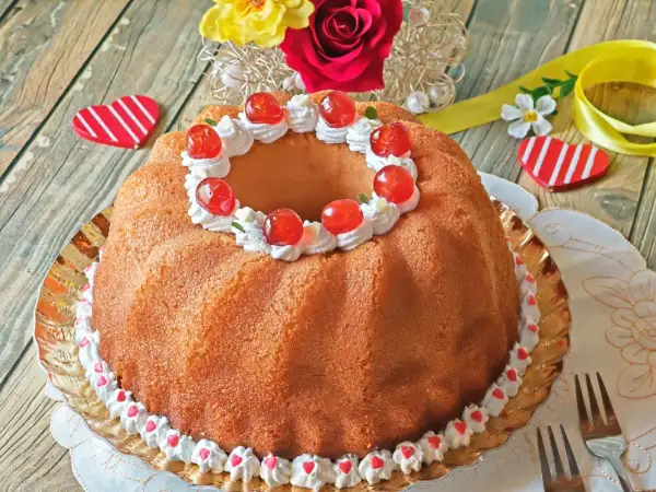 Un delicioso baba postre decorado con crema batida y cerezas rojas, listo para celebrar el amor.