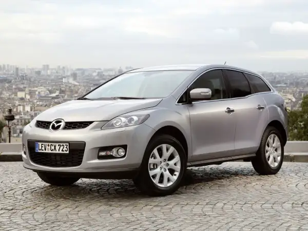 Srebrna Mazda CX-7 2.3 Turbo na tle panoramy miasta.