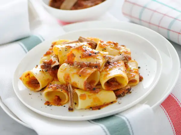 Une assiette de paccheri généreusement nappés d'une sauce tomate riche et de morceaux de viande savoureux. Ce plat de pâtes à la viande est un délice réconfortant.