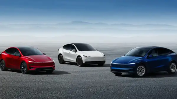 Trzy samochody Tesla: czerwony, biały i niebieski, stoją na pustkowiu.