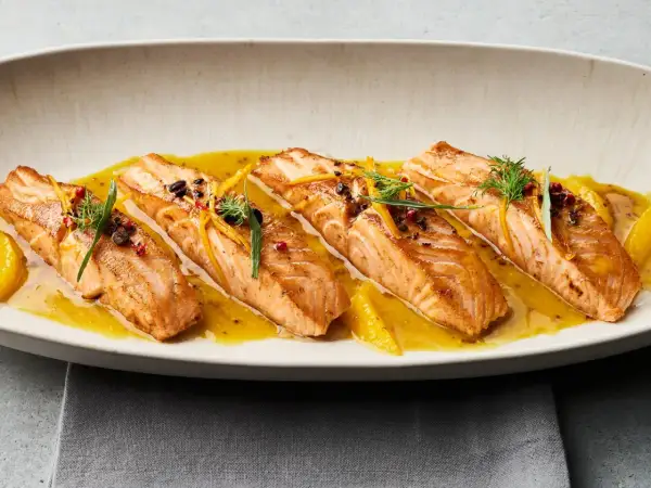 Gebratene Lachsfilets auf einer Zitrussoße, garniert mit Dill und Orangenzesten. Tolle Ideen für eine Fischplatte!