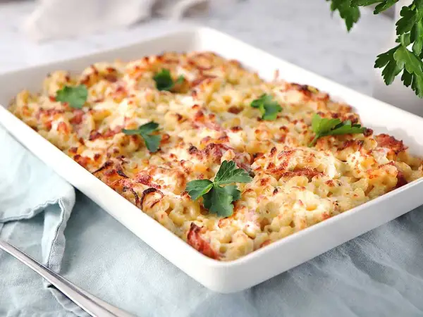 En krämig gratäng med makaroner, ost och bacon, perfekt för ett gott ostsås recept. Garnerad med färsk persilja.