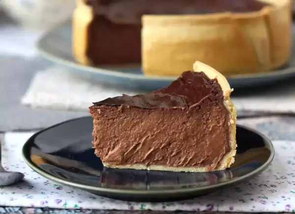 Rebanada de flan de chocolate con cobertura brillante, servida en plato oscuro.
