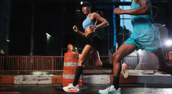 Coppia di runner notturni in città, impegnati in esercizi per migliorare la corsa. Le luci urbane illuminano la loro determinazione.
