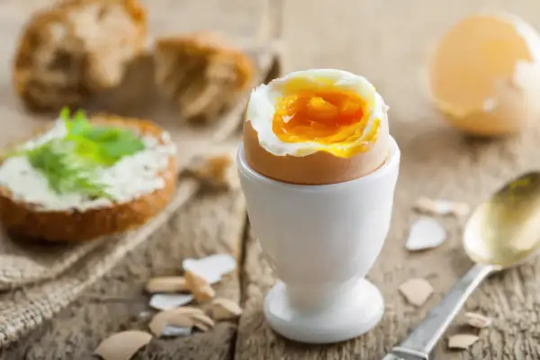 Un huevo duro 8 minutos con la yema líquida, listo para disfrutar con pan tostado y mantequilla.