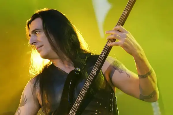 Bassist mit langen Haaren spielt auf einer E-Gitarre, die Hände auf dem Griffbrett. Er ist Teil der lauteste band der welt.