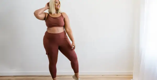 Kobieta plus size w brązowym komplecie sportowym, legginsy z kieszeniami.