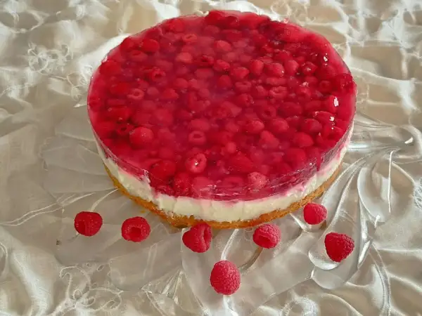 Himbeer-Curd-Torte mit frischen Himbeeren und glänzender Tortenguss-Schicht auf einem cremigen Boden. Ein Genuss für Augen und Gaumen.