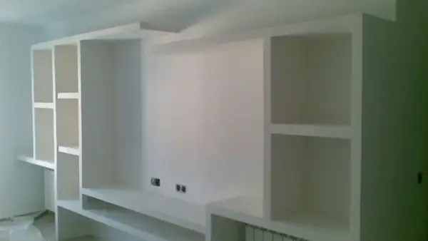 Parete attrezzata fai da te in cartongesso, con vani a giorno e mensole, pronta per accogliere TV e oggetti.