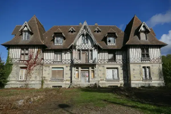 Maison abandonnée en Normandie, typique de l'urbex. Façade en colombage et pierre, toiture pentue, fenêtres brisées.