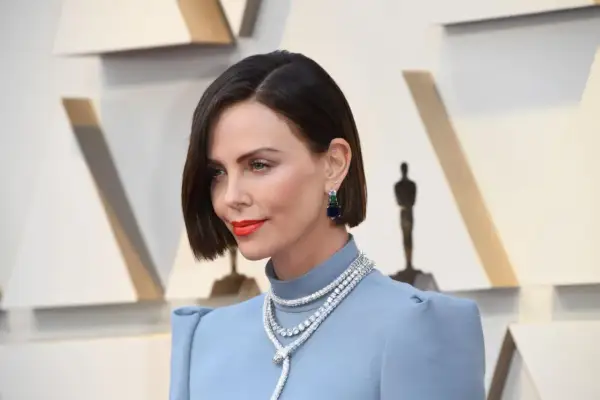 Charlize Theron con un elegante caschetto corto pari, orecchini pendenti e una collana scintillante.