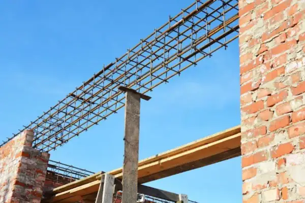 Siatka zbrojeniowa nadproża 3m, gotowa do zalania betonem, na tle błękitnego nieba i ceglanej ściany.