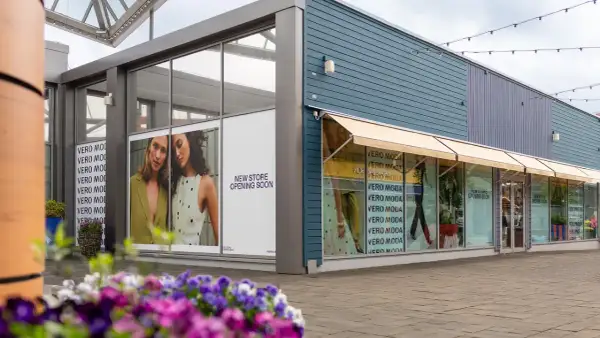 Vero Moda outlet med skyltar som visar "New Store Opening Soon". Blommor i förgrunden.