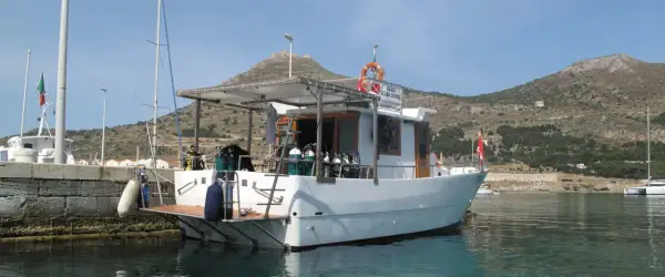 Barca da sub con bombole pronte per il battesimo dello scafo. Sullo sfondo, un castello su una collina.