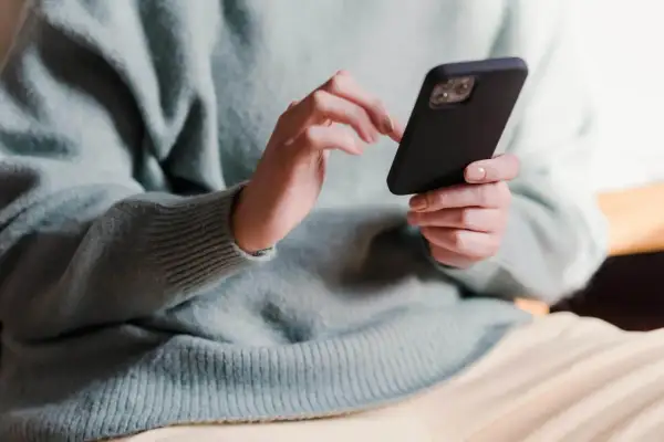 Dłonie trzymające telefon, zastanawiające się, co napisać po kłótni.