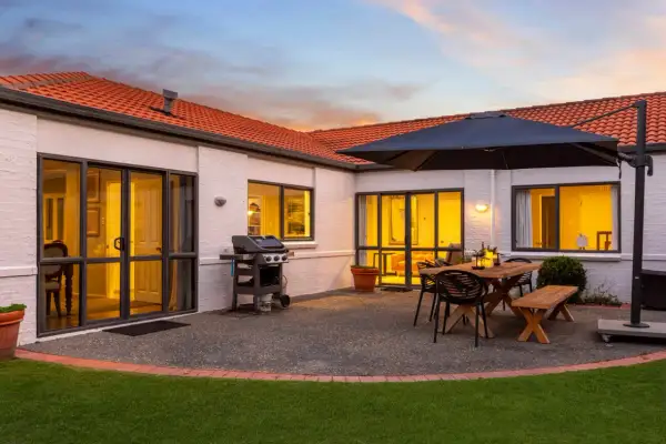 Beautiful house photography showcasing a patio with a BBQ, dining set, and umbrella, ready for entertaining.