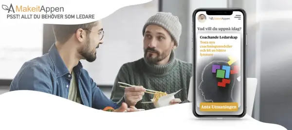 Två män äter lunch och pratar. En mobil visar appen MakeitAppen med en utmaning för coachande ledarskap, ett bra sätt att visa uppskattning på jobbet.