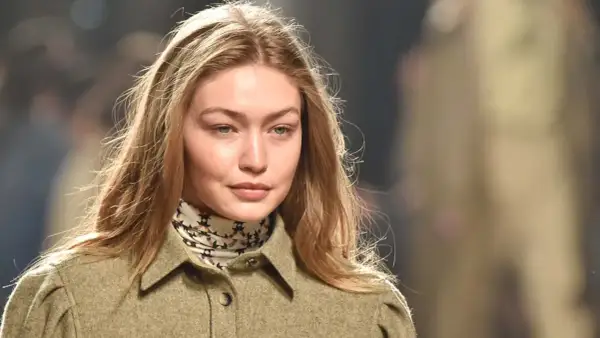 Modelo con cabello rubio y mechas blancas, viste una chaqueta verde y un pañuelo estampado.
